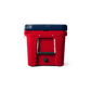A side view of the limited edition YETI Tundra 45 in Patriotic Red, White, and Blue. The top lid is navy blue, the base of the cooler is red, and the handles on the side are white, with a black hand grip. There is a number 45 engraved into the side of the cooler, also in the color red. The water drain on the cooler is the color black.