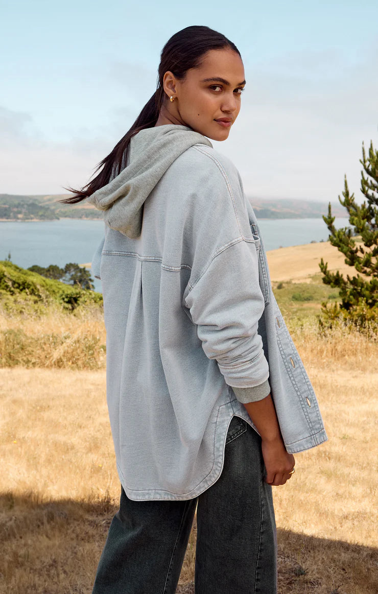 Z Supply model with black hair, wearing the All Day Knit Denim Jacket. The jacket features 6 front buttons, two chest pockets, and a collared top.