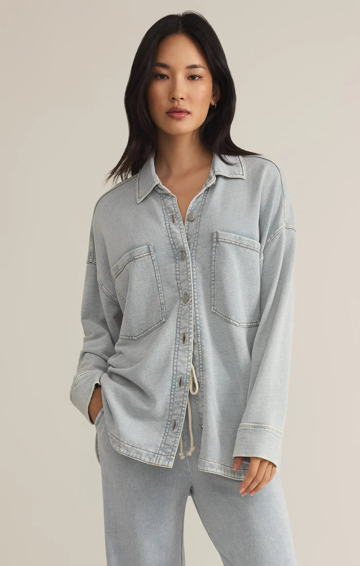 Z Supply model with black hair, wearing the All Day Knit Denim Jacket. The jacket features 6 front buttons, two chest pockets, and a collared top.