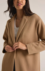 Tan colored mason coat from the brand Z-Supply. The coat has one button and it's length goes past the knees.