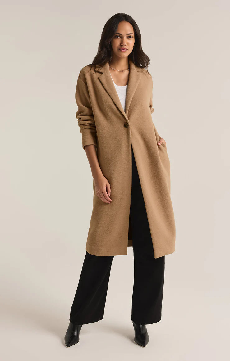 Tan colored mason coat from the brand Z-Supply. The coat has one button and it's length goes past the knees.