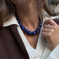 BaubleBar Jane Beaded Necklace in Blue worn with a white V-neck top and brown cardigan