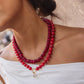 Model wearing the red BaubleBar Joyce necklace layered with a separate pendant necklace