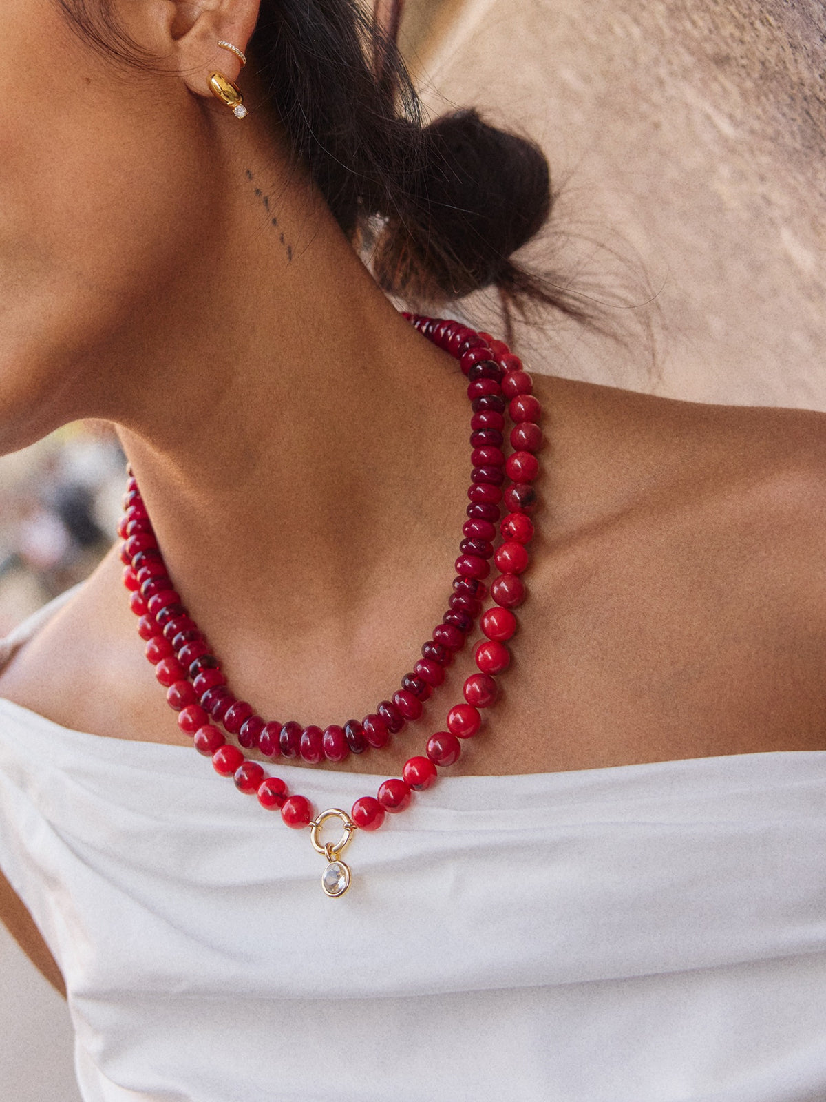 Model wearing the red BaubleBar Joyce necklace layered with a separate pendant necklace