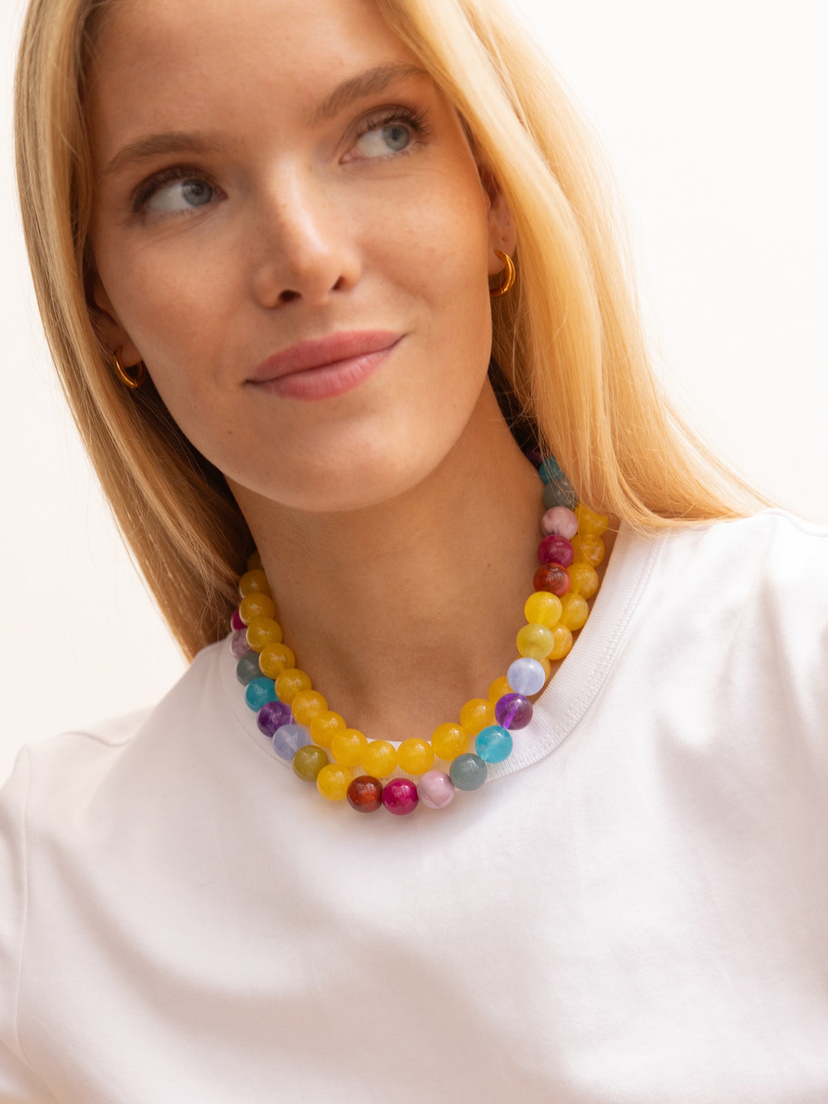 Model wearing the BaubleBar Mini Jane Beaded Necklace in Multi layered with a yellow necklace over a white top.