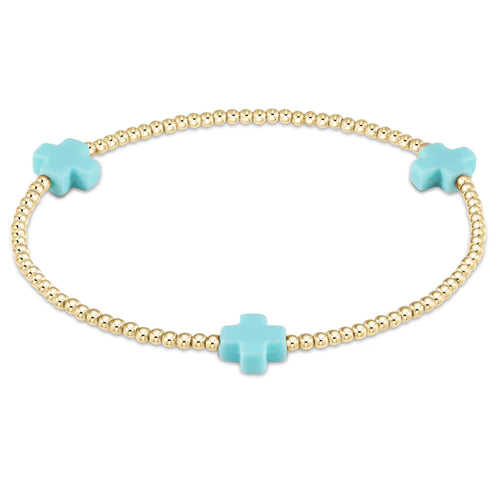 A gold beaded bracelet from enewton with turquoise crosses.