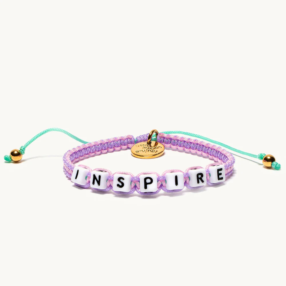 A woven bracelet that's purple and turquoise with the word 'inspire'.