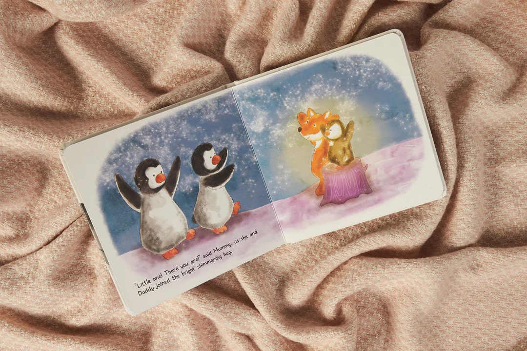 Inside the book with two pages showing two penguins on the left, and a fox with a penguin on the right.